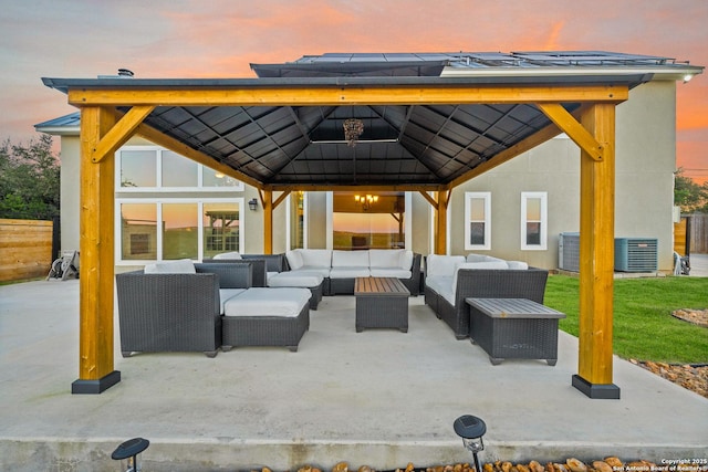 patio terrace at dusk with a gazebo, an outdoor hangout area, and central AC