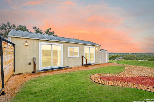 back house at dusk featuring a yard and an outdoor structure