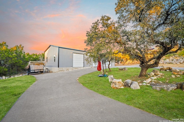 view of front facade with a garage, an outdoor structure, and a lawn