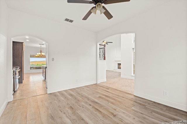 unfurnished room with light wood-type flooring and ceiling fan with notable chandelier