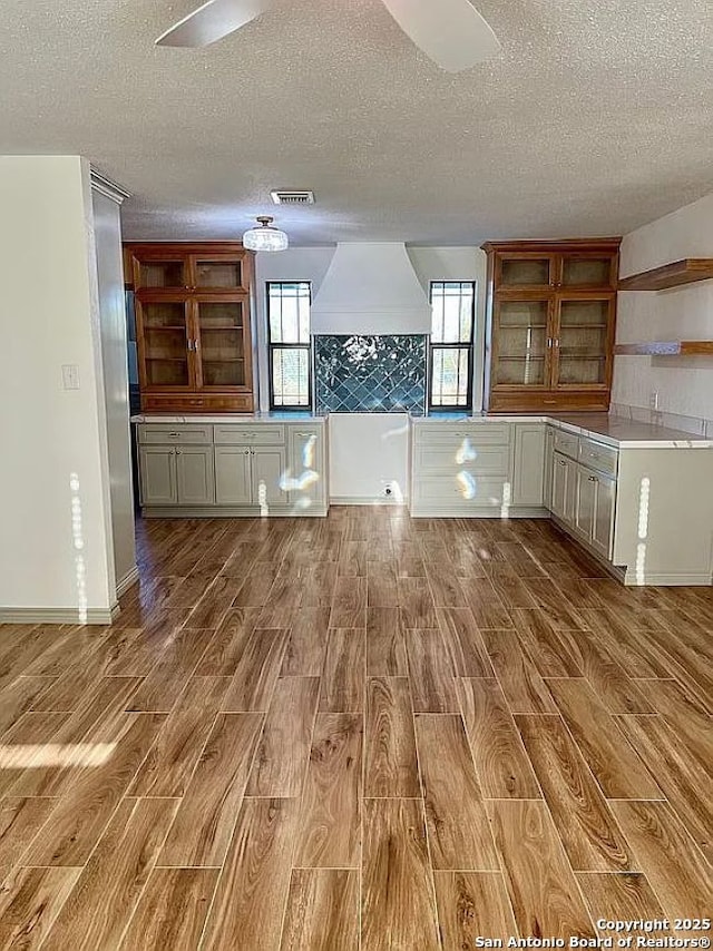 kitchen featuring custom exhaust hood, light hardwood / wood-style floors, white cabinets, and plenty of natural light