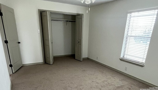 unfurnished bedroom featuring light carpet and a closet