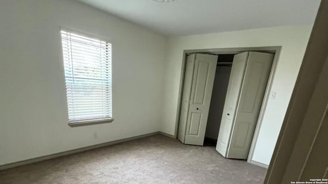 unfurnished bedroom featuring light carpet and a closet