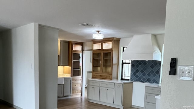 kitchen with decorative backsplash, dark wood-type flooring, custom range hood, and white cabinets