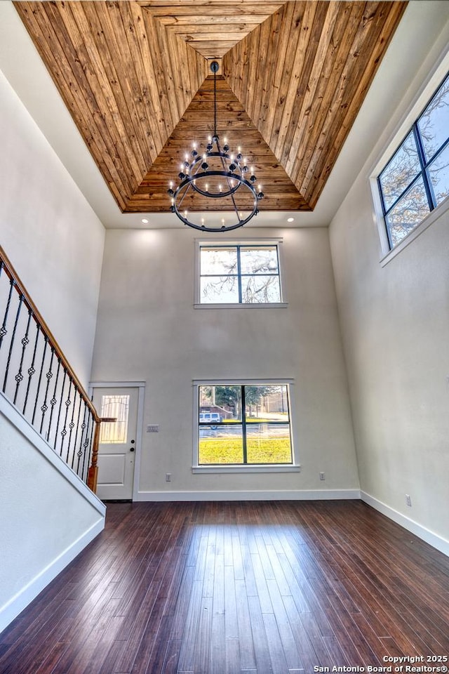 unfurnished living room featuring dark wood-type flooring, wooden ceiling, and a notable chandelier