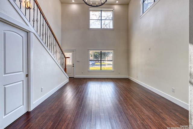 unfurnished living room with a notable chandelier, plenty of natural light, and dark hardwood / wood-style floors