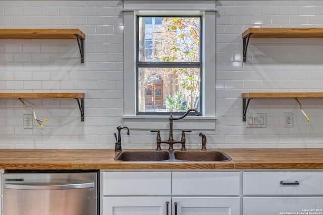 kitchen with tasteful backsplash, white cabinetry, dishwasher, and wood counters