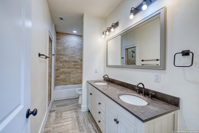 full bathroom featuring tiled shower / bath, vanity, and toilet