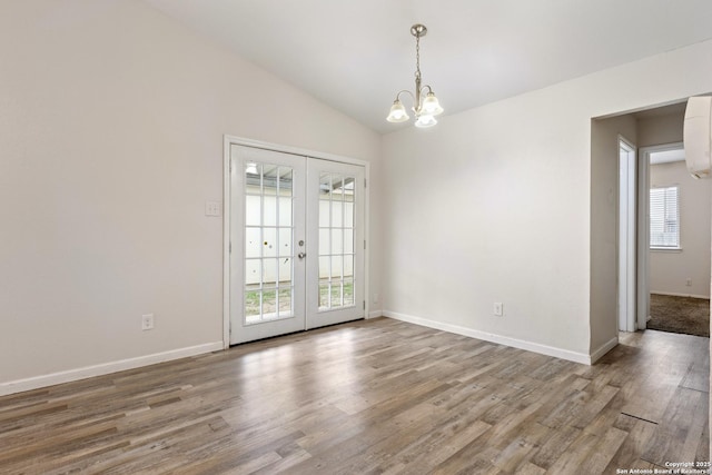 spare room featuring french doors, wood-type flooring, lofted ceiling, and a notable chandelier