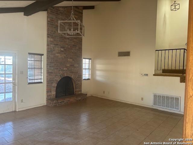 unfurnished living room featuring a fireplace, beam ceiling, high vaulted ceiling, and tile patterned floors