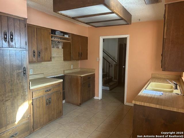 kitchen with decorative backsplash, sink, and a textured ceiling