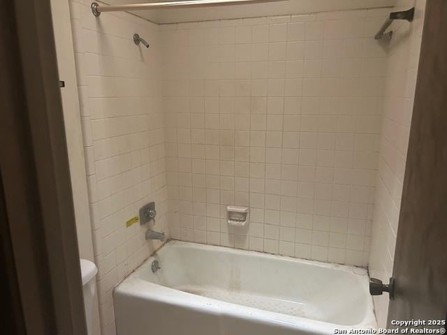 bathroom featuring tiled shower / bath combo and toilet