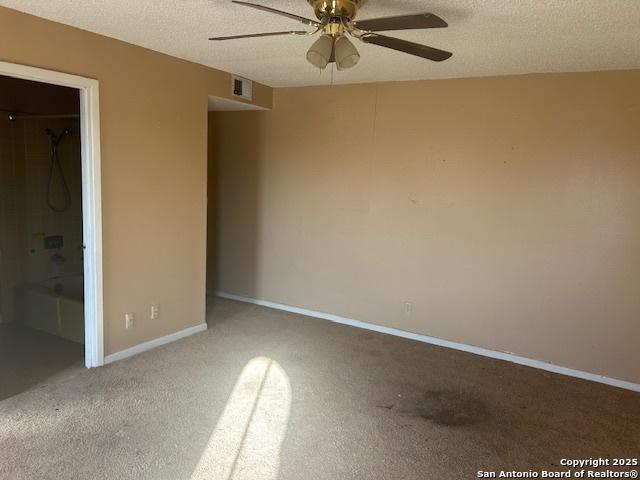 unfurnished bedroom featuring a walk in closet, ceiling fan, carpet, and a textured ceiling