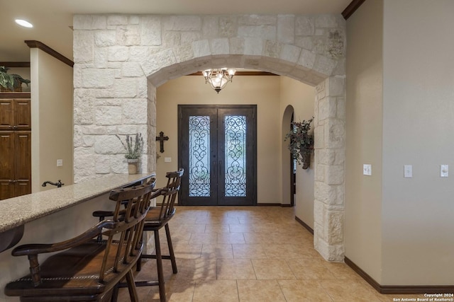 foyer entrance featuring french doors, crown molding, and a notable chandelier