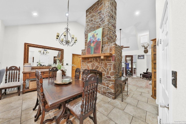 dining area with a stone fireplace, high vaulted ceiling, and an inviting chandelier