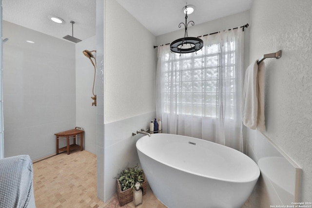 bathroom featuring plus walk in shower and tile walls