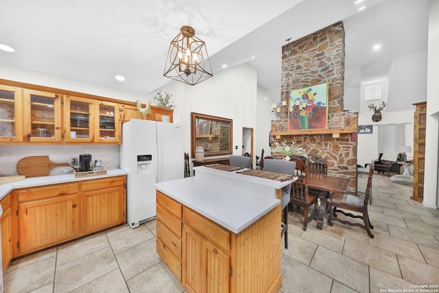 kitchen with decorative light fixtures, white fridge with ice dispenser, a fireplace, a notable chandelier, and a kitchen island