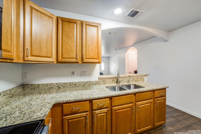 kitchen featuring light stone countertops, range, and sink