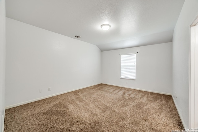 carpeted empty room with a textured ceiling and vaulted ceiling