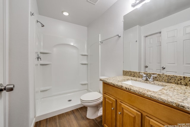 bathroom with wood-type flooring, vanity, toilet, and walk in shower