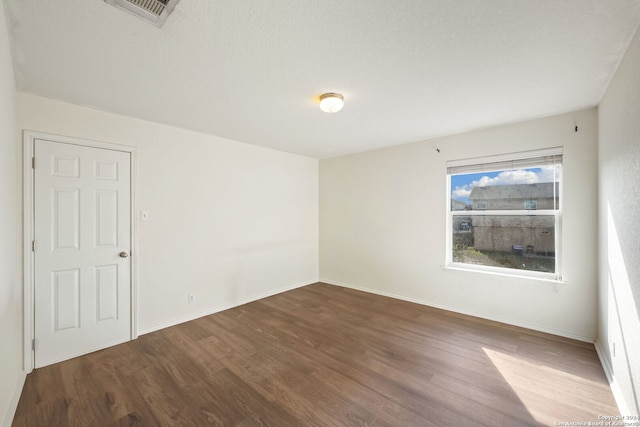 empty room with a textured ceiling and hardwood / wood-style flooring