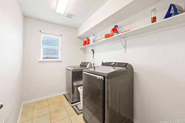 clothes washing area featuring washer and clothes dryer and light tile patterned flooring