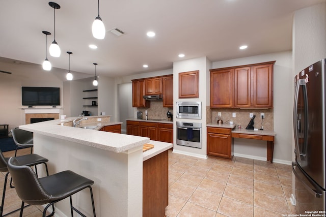 kitchen with pendant lighting, a kitchen bar, stainless steel appliances, and tasteful backsplash