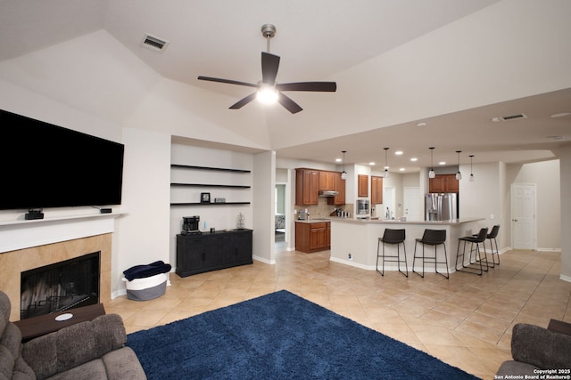 living room with a tiled fireplace, ceiling fan, light tile patterned floors, and vaulted ceiling