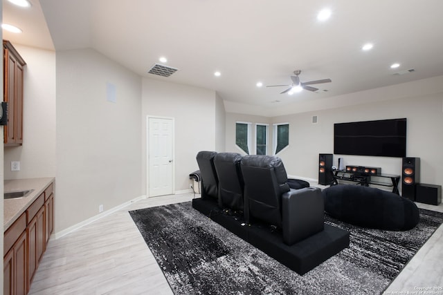 home theater room with light wood-type flooring and ceiling fan