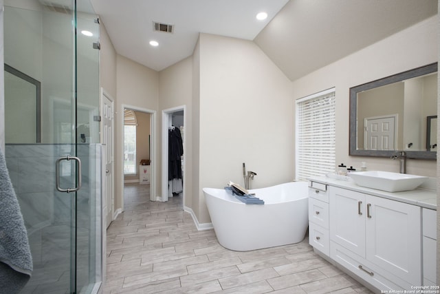 bathroom featuring vanity, vaulted ceiling, and shower with separate bathtub