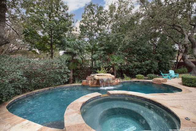 view of swimming pool featuring pool water feature and an in ground hot tub