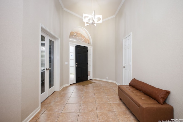 entrance foyer featuring light tile patterned floors, a towering ceiling, an inviting chandelier, and ornamental molding