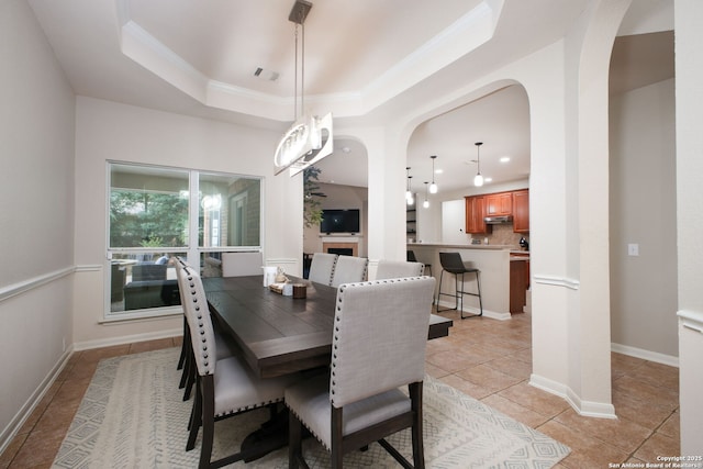 tiled dining space featuring a tray ceiling and ornamental molding