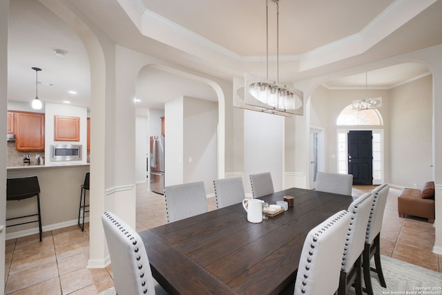 dining room featuring a tray ceiling, crown molding, light tile patterned floors, and an inviting chandelier