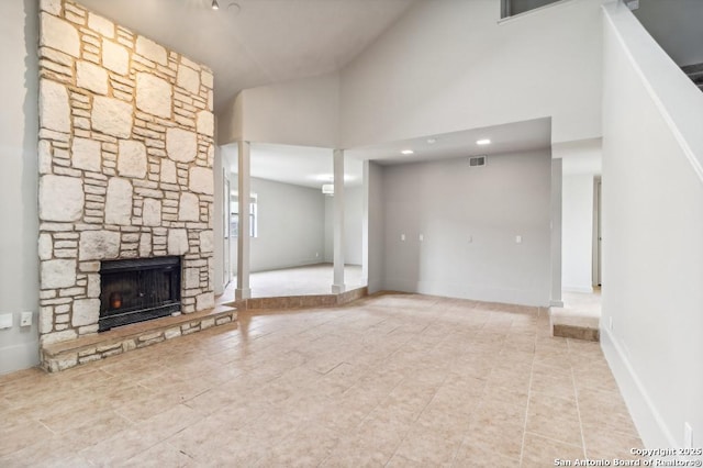 unfurnished living room with a stone fireplace and a high ceiling