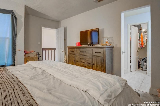 bedroom with a spacious closet, light tile patterned floors, and a closet