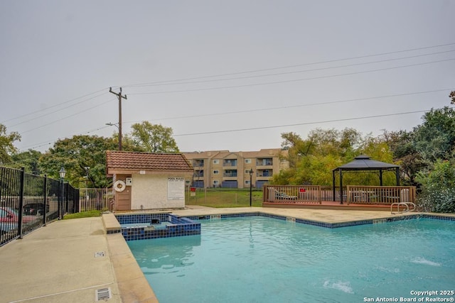 view of pool featuring a gazebo, pool water feature, and a hot tub