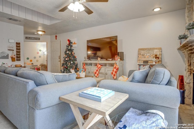 living room featuring ceiling fan and a textured ceiling