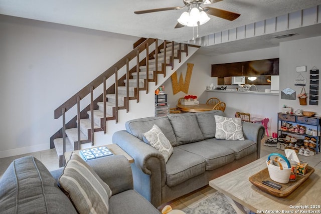 tiled living room featuring ceiling fan and a textured ceiling