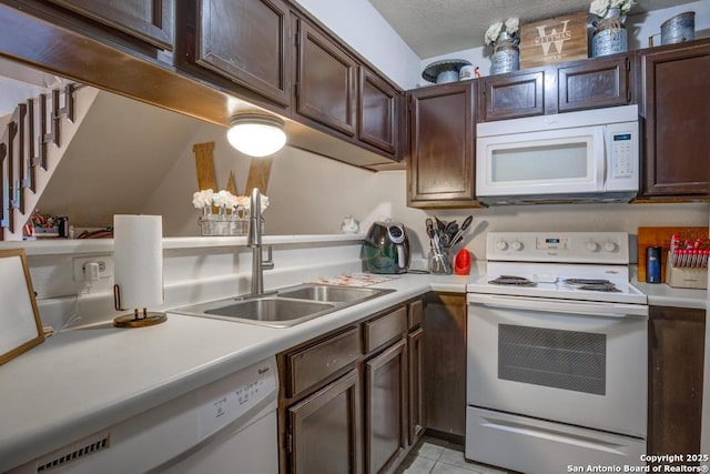 kitchen with dark brown cabinets, white appliances, light tile patterned floors, and sink