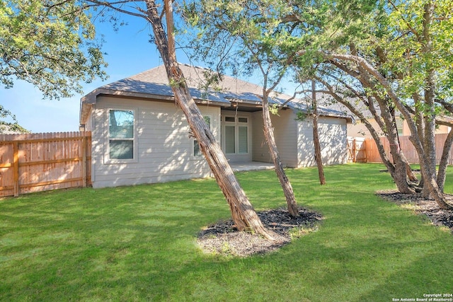 rear view of house with roof with shingles, french doors, a lawn, and fence