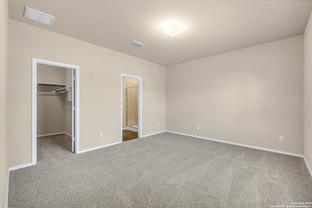 unfurnished bedroom featuring carpet flooring, a spacious closet, and a closet