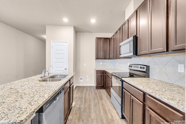 kitchen featuring light stone countertops, sink, stainless steel appliances, tasteful backsplash, and light hardwood / wood-style flooring