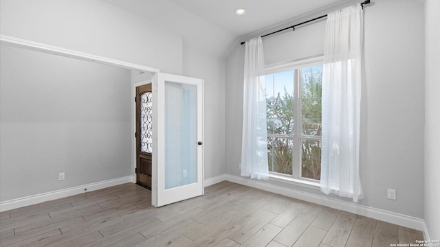 unfurnished room with french doors, light wood-type flooring, and lofted ceiling