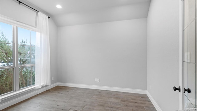 empty room featuring light hardwood / wood-style floors and vaulted ceiling