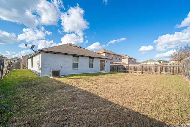 rear view of property featuring a lawn and central air condition unit