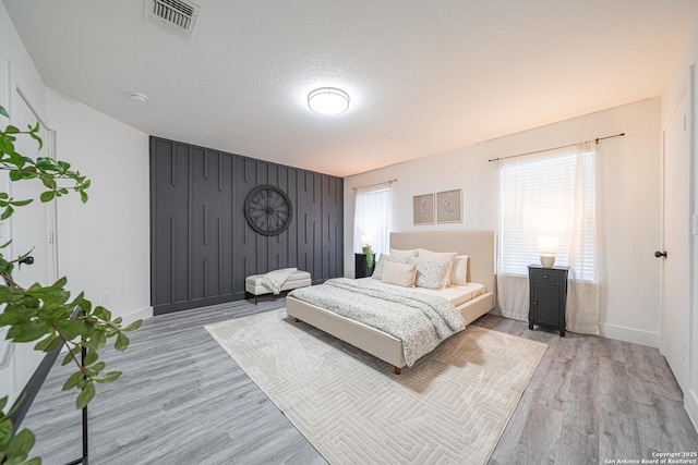 bedroom with a textured ceiling and light hardwood / wood-style flooring