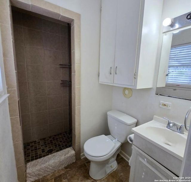 bathroom featuring tile patterned floors, toilet, vanity, and tiled shower