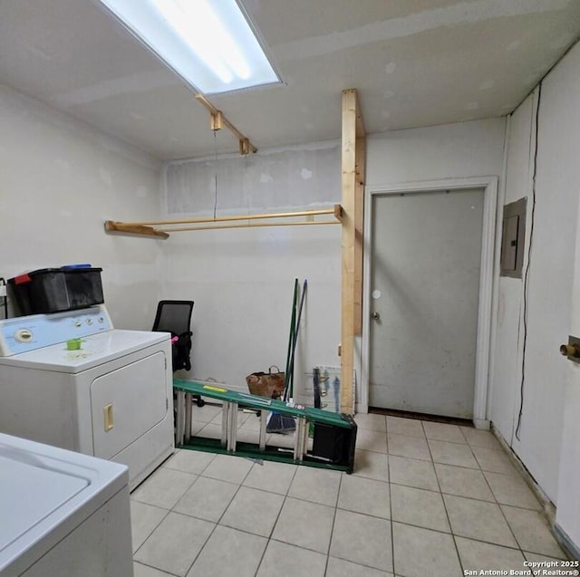 washroom featuring light tile patterned floors, electric panel, and washing machine and clothes dryer