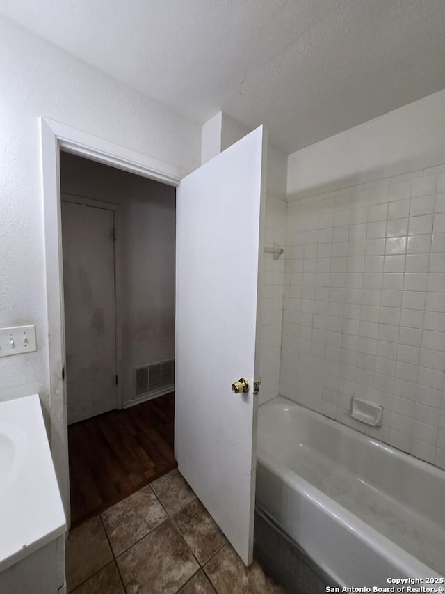 bathroom featuring tile patterned flooring, vanity, and tiled shower / bath